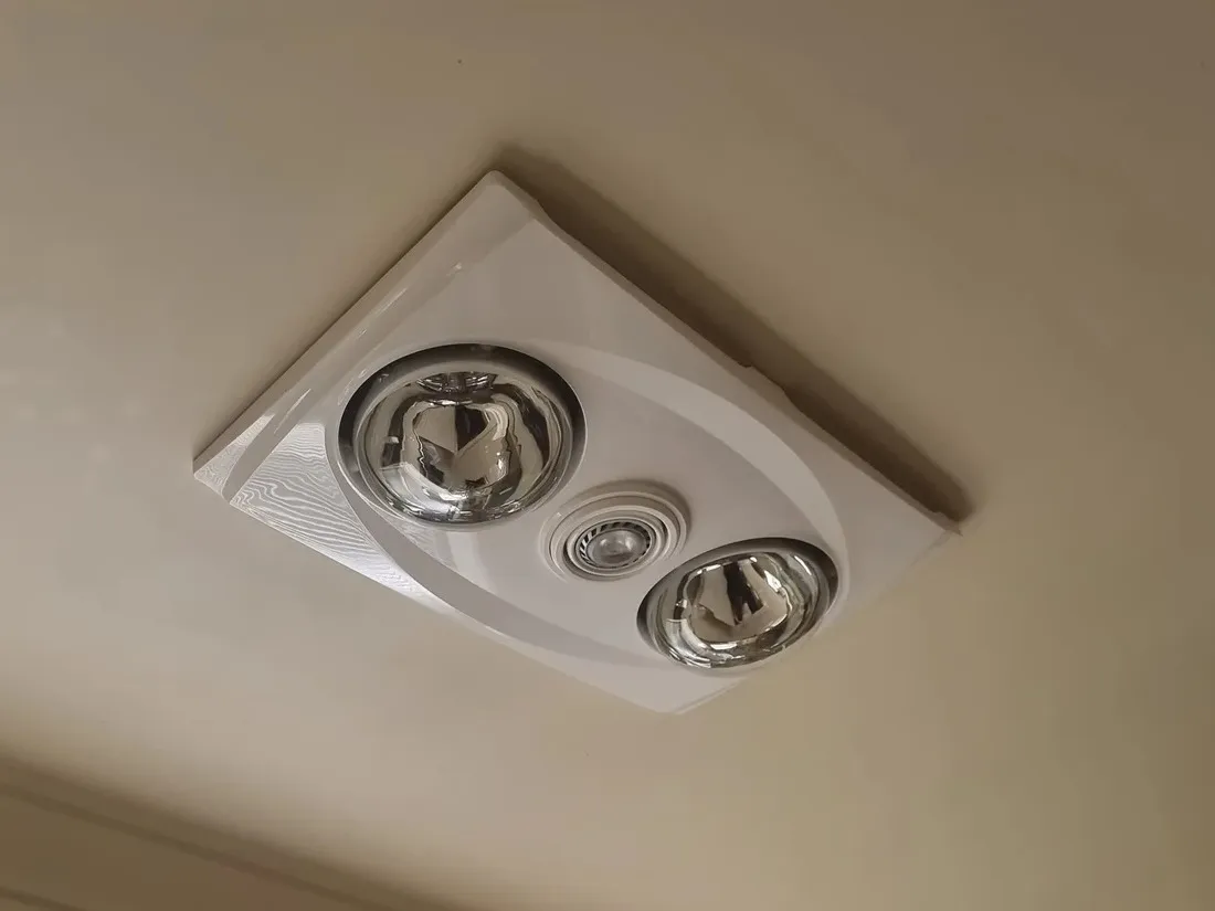 A white heat, light and fan unit fitted in a bathroom ceiling.